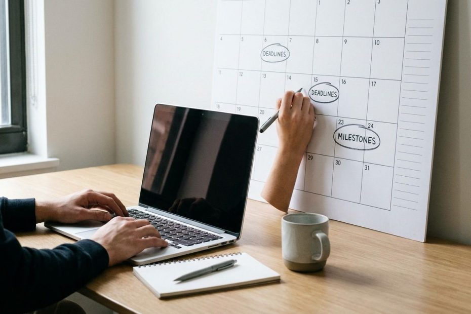 Student planning semester deadlines with a notebook, calendar, and laptop at a study desk